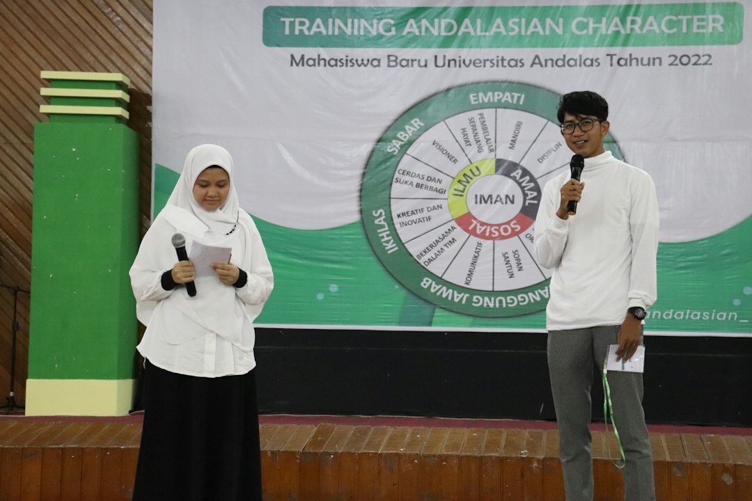 Lecturer coaching a trainee moderator at a microphone